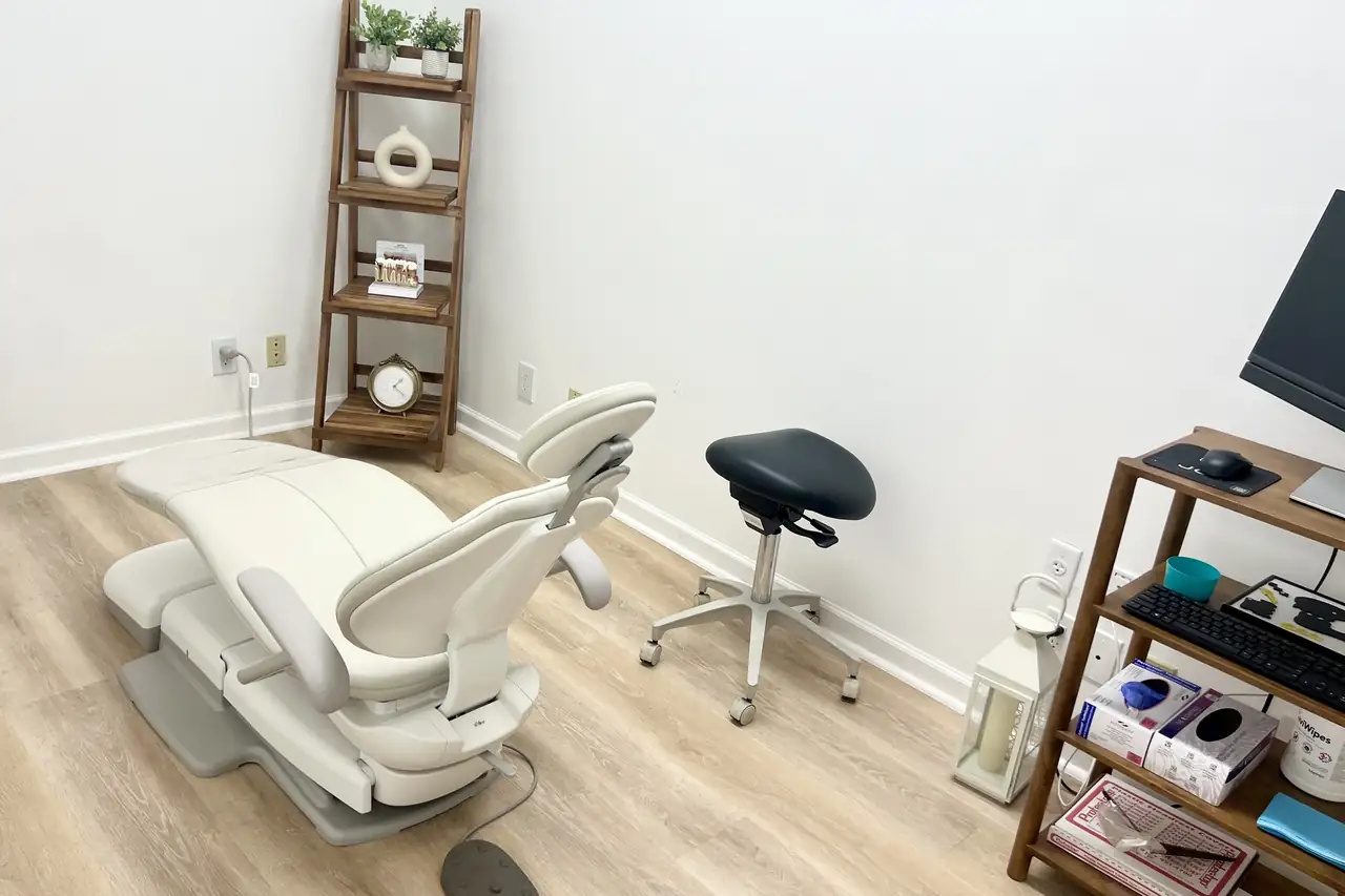 A treatment room at Jupiter Implant & Cosmetic Dentistry, with a dental chair, wood floor and shelves.