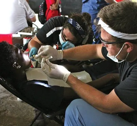 Dr. Shane with a young patient and a volunteer in Belize.