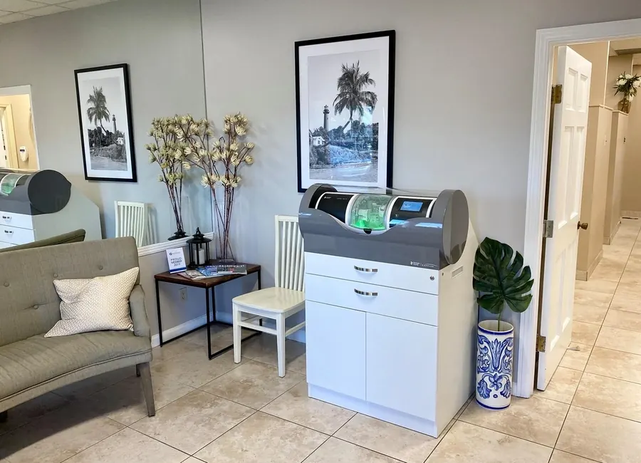 The reception area, with a sofa, framed palm prints and the CEREC unit.